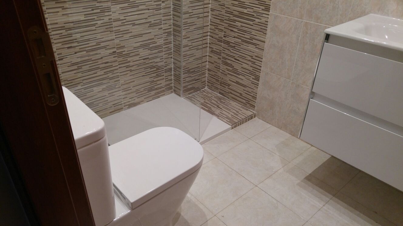 El mismo baño después: ducha a ras de suelo con mosaico y mueble suspendido
