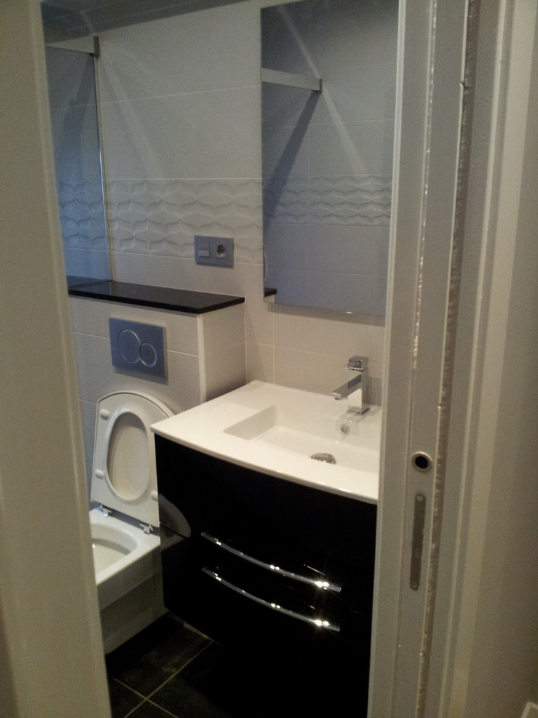 Baño completo en blanco y negro con mueble suspendido y cisterna empotrada