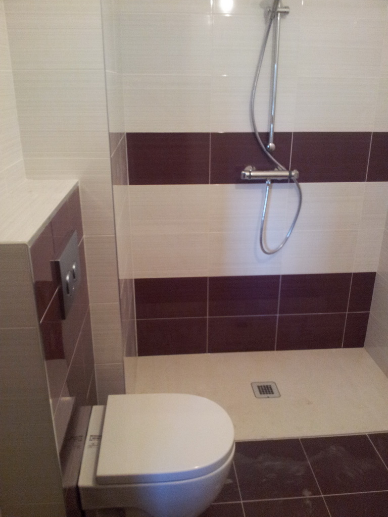 Ducha a ras de suelo en baño burdeos y blanco con inodoro suspendido